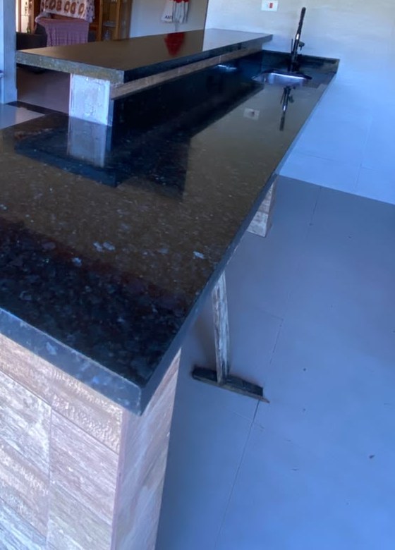 Bancada longa em granito preto em área gourmet