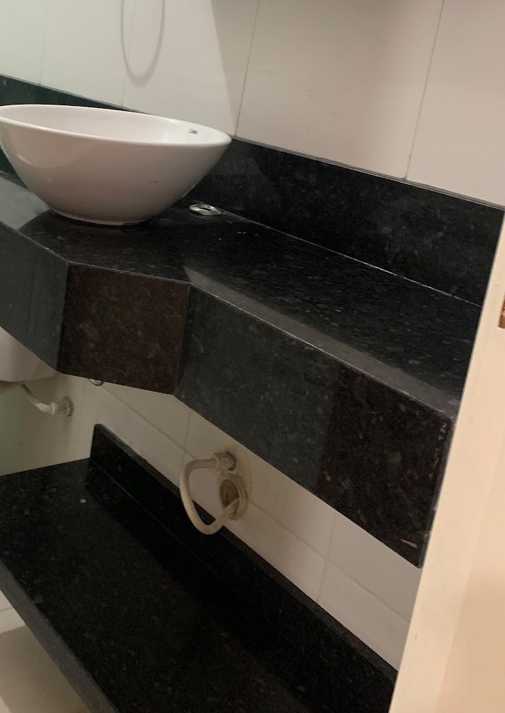 Bancada de lavabo em granito preto com cuba de apoio e prateleira